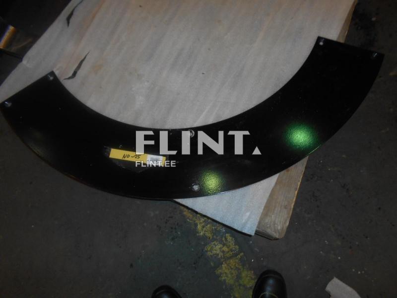 Mustast metallist kaarjas detail, millel on mitu avatud auku ja etikett küljes. Detail asetatud eristuva pinnaga pinna peale.