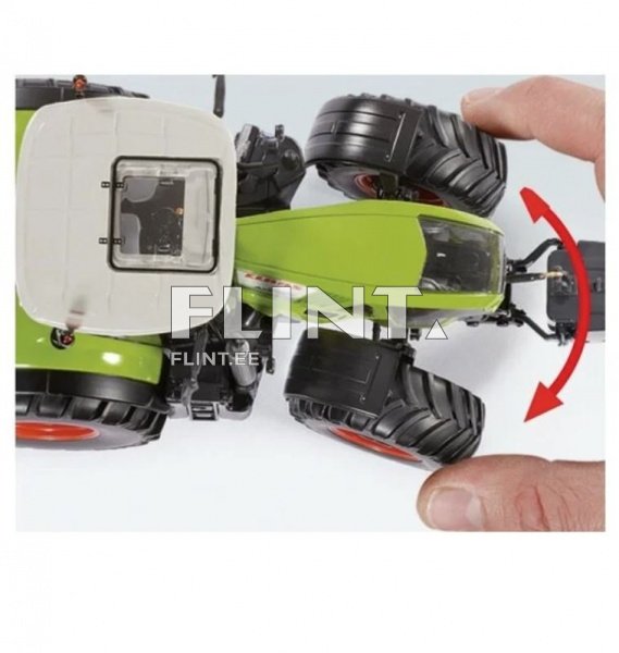 Pildil on väiketraktor, millel on rohelised külged ja mustad suured rehvid. Traktori kohal on valge kattega kabiin, millel on aken. Pildi paremal pool on näha sõrme, mis puudutab traktorit ning seda on pööratud vasakule poole.