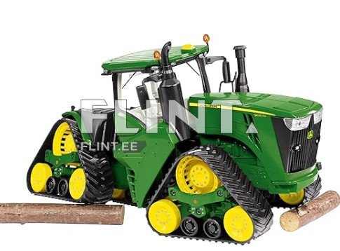 Roheline traktori mudel, millel on suured kollased rattad ja mustad radiaatorid. Traktoril on nähtavad puutükid ees, mis on skaalal detailseid. Sõiduki kabin on avatud, ja see on mudelitud jooned ja kurvid.