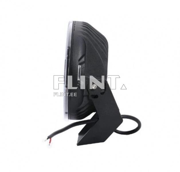 Seade on musta värvi valgusallikas, millel on ümmargune kuju. Korpuse küljes on kinnitustugi ja nähtav juhtmeosa, mis ulatub välja. Korpuse külgedel on reljeefsed jooned.