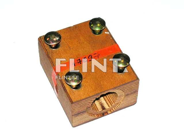 Puitkast, millel on neli metallist nuppu. Kastil on sees avaus ja see on tähistatud punase lindiga.