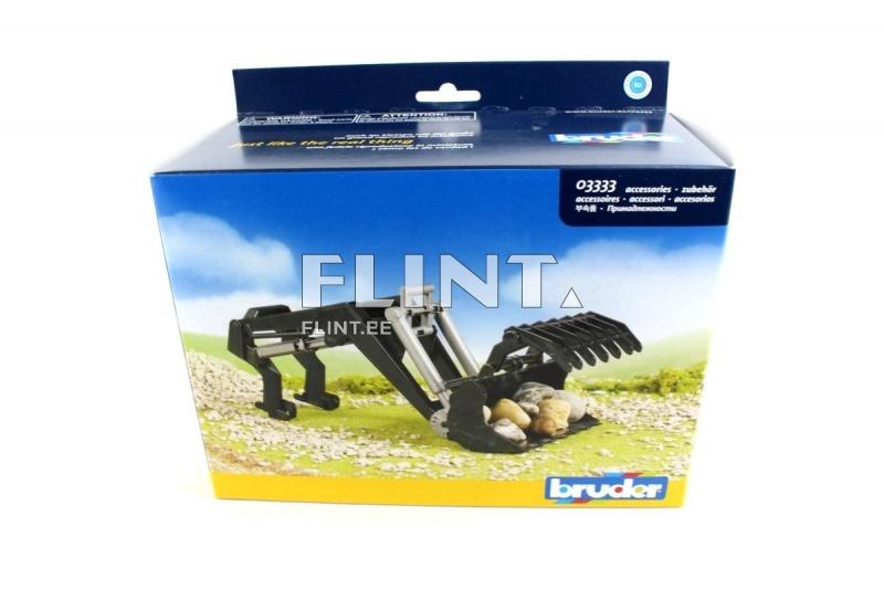 Pakendi esiküljel on must miniekskavaator, millel on kivide korjamise lisaseade. Taustal on rohelised maastikud ja sinine taevas.