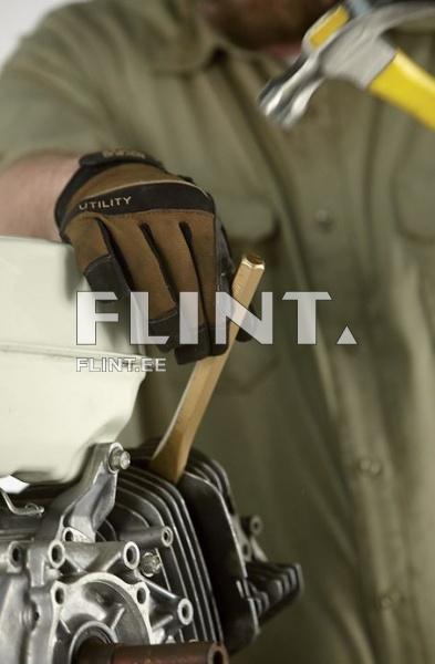 Pildil on käsi, mis kannab musta ja pruuni töökindaid, hoides puidust tööriista mootoriploki kohal. Taustal on hall käsi, millel on haamri käepide. Mootoril on hõbedane metallpind ja valge kaan.