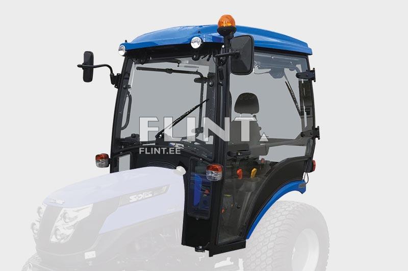 Sinine traktorikabiin, millel on selged aknad ja ümar katuseosa. Kabiini esiosas on nähtavad rool ja istme kohal olev juhtpaneel.