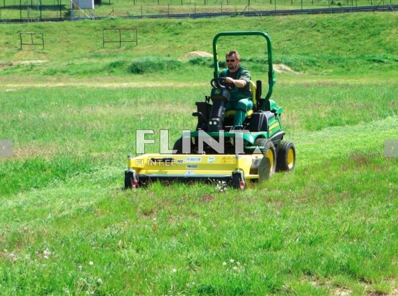 Aednik sõidab rohelisest muruniidukist, millel on kollane niiduk, rohelisel murul.